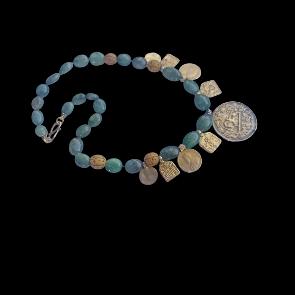 Collar con antigua moneda iraní representando un león empuñando una espada , con un sol detrás, convertida en colgante, combinada en en esta pieza unica de Lula Máiz con amuletos antiguos de plata dorada y monedas de principios de siglo XX de India, esmeraldas y antiguas cuentas de intercambio, de vidrio de Murano. El cierre es contemporaneo, de plata de ley con baño de oro. Longitud 48 cm Peso 73 gramos One of a kind necklace by Lula Máiz