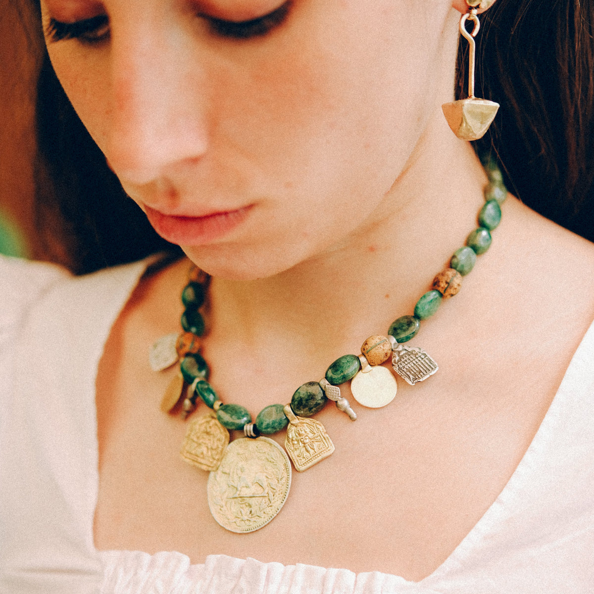 Collar con antigua moneda iraní representando un león empuñando una espada , con un sol detrás, convertida en colgante, combinada en en esta pieza unica de Lula Máiz con amuletos antiguos de plata dorada y monedas de principios de siglo XX de India, esmeraldas y antiguas cuentas de intercambio, de vidrio de Murano. El cierre es contemporaneo, de plata de ley con baño de oro. Longitud 48 cm Peso 73 gramos One of a kind necklace by Lula Máiz