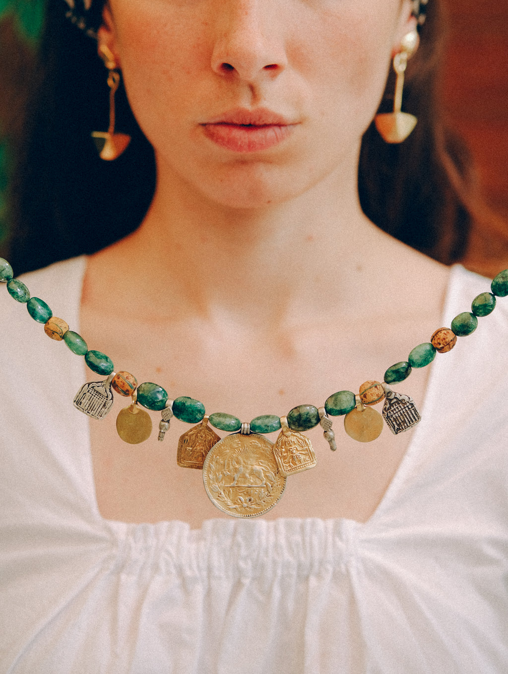 Collar con antigua moneda iraní representando un león empuñando una espada , con un sol detrás, convertida en colgante, combinada en en esta pieza unica de Lula Máiz con amuletos antiguos de plata dorada y monedas de principios de siglo XX de India, esmeraldas y antiguas cuentas de intercambio, de vidrio de Murano. El cierre es contemporaneo, de plata de ley con baño de oro. Longitud 48 cm Peso 73 gramos One of a kind necklace by Lula Máiz