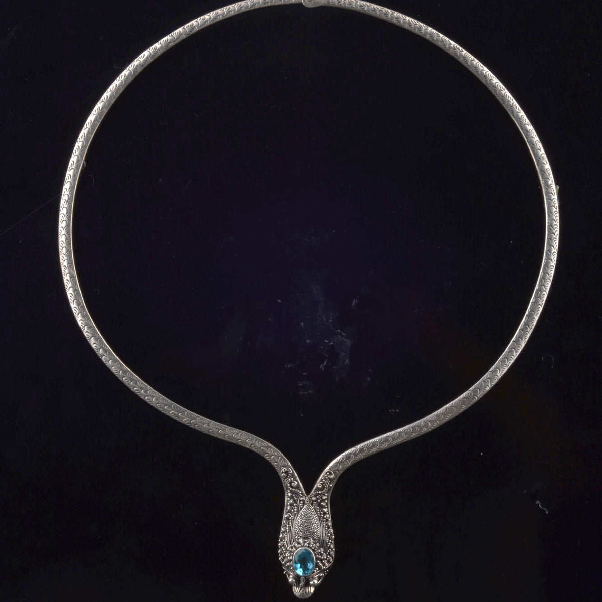 Collar artesanal hecho a mano con plata de ley y topacio azul, y forma de dragón. La pureza de la plata hace que sea muy maleable y se pueda adaptar fácilmente al cuello. Contorno interior 47 cm Peso 35 g. Necklace hand made with sterling silver and blue topaz in the shape of a dragon. Lula Máiz