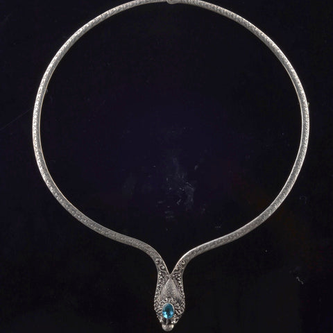 Collar artesanal hecho a mano con plata de ley y topacio azul, y forma de dragón. La pureza de la plata hace que sea muy maleable y se pueda adaptar fácilmente al cuello. Contorno interior 47 cm Peso 35 g. Necklace hand made with sterling silver and blue topaz in the shape of a dragon. Lula Máiz