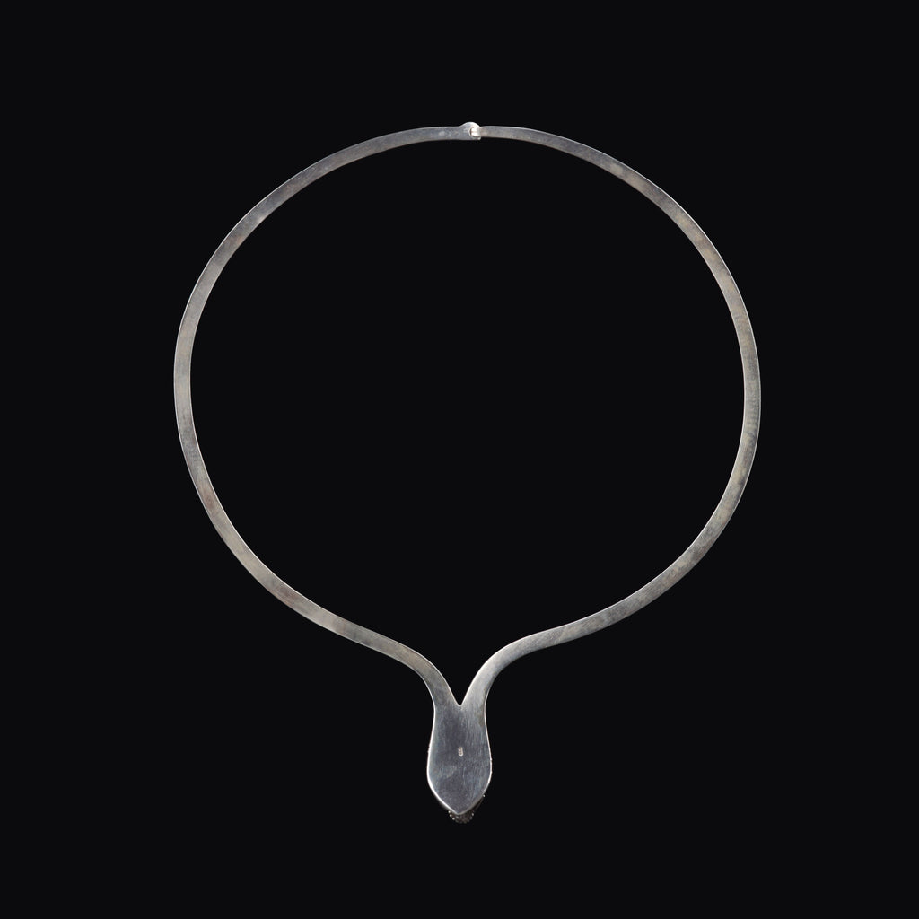 Collar artesanal hecho a mano con plata de ley y topacio azul, y forma de dragón. La pureza de la plata hace que sea muy maleable y se pueda adaptar fácilmente al cuello. Contorno interior 47 cm Peso 35 g. Necklace hand made with sterling silver and blue topaz in the shape of a dragon. Lula Máiz