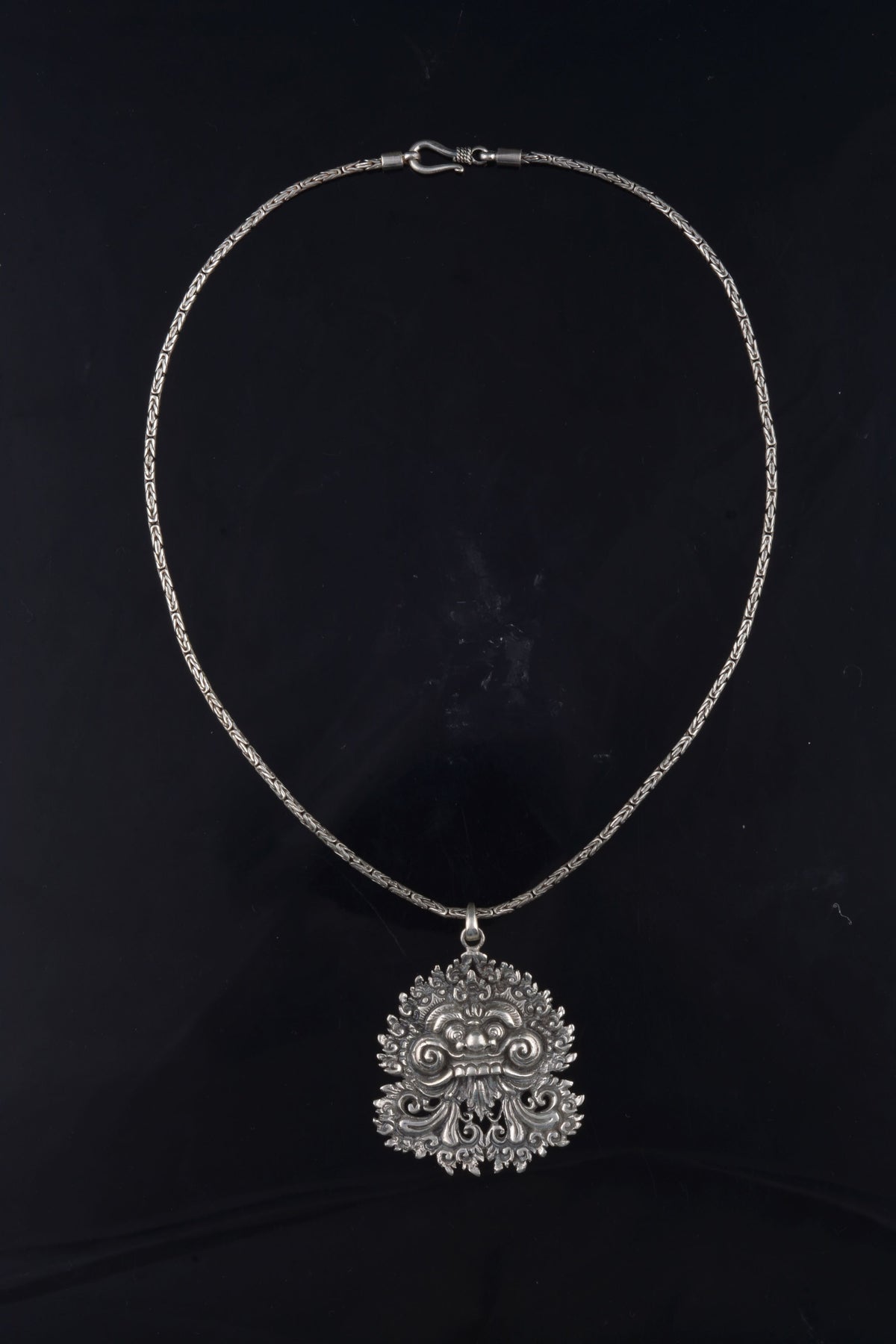 Colgante artesanal hecho a mano con plata de ley representando a Barong, criatura mítica de la isla de Bali, rey de los espíritus del bien, que adopta forma de animal como protector del bosque. Medidas 5 cm x 4 cm Largo cadena 45 cm Peso colgante 19 g Peso cadena 14 g Handcrafted silver pendant. Lula Máiz