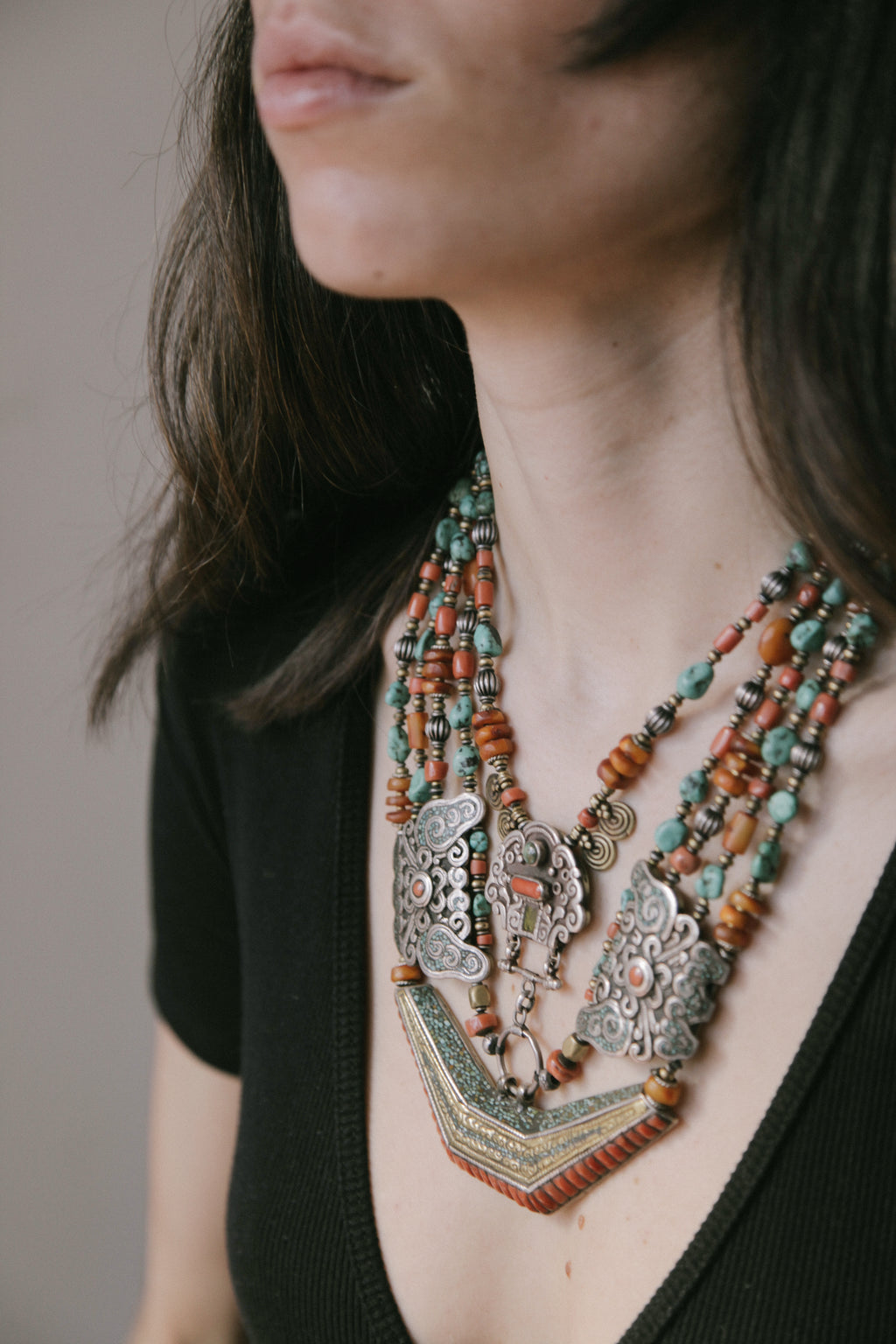 Collar de Tíbet hecho a mano con un maravilloso detalle en el labrado de la plata( representando dos mariposas en los laterales ) engarzado con cuatro vueltas de cuentas de plata, bronce, coral, turquesa, y ámbar,  gemas favoritas de la joyería tradicional tibetana. El cierre con coral y turquesa. Longitud 55 cm Peso  190 g.Tibetan necklace.