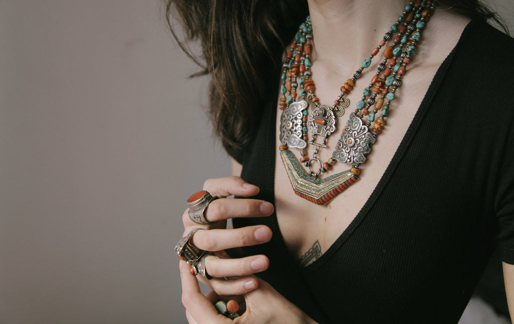 Collar de Tíbet hecho a mano con un maravilloso detalle en el labrado de la plata( representando dos mariposas en los laterales ) engarzado con cuatro vueltas de cuentas de plata, bronce, coral, turquesa, y ámbar,  gemas favoritas de la joyería tradicional tibetana. El cierre con coral y turquesa. Longitud 55 cm Peso  190 g.Tibetan necklace.