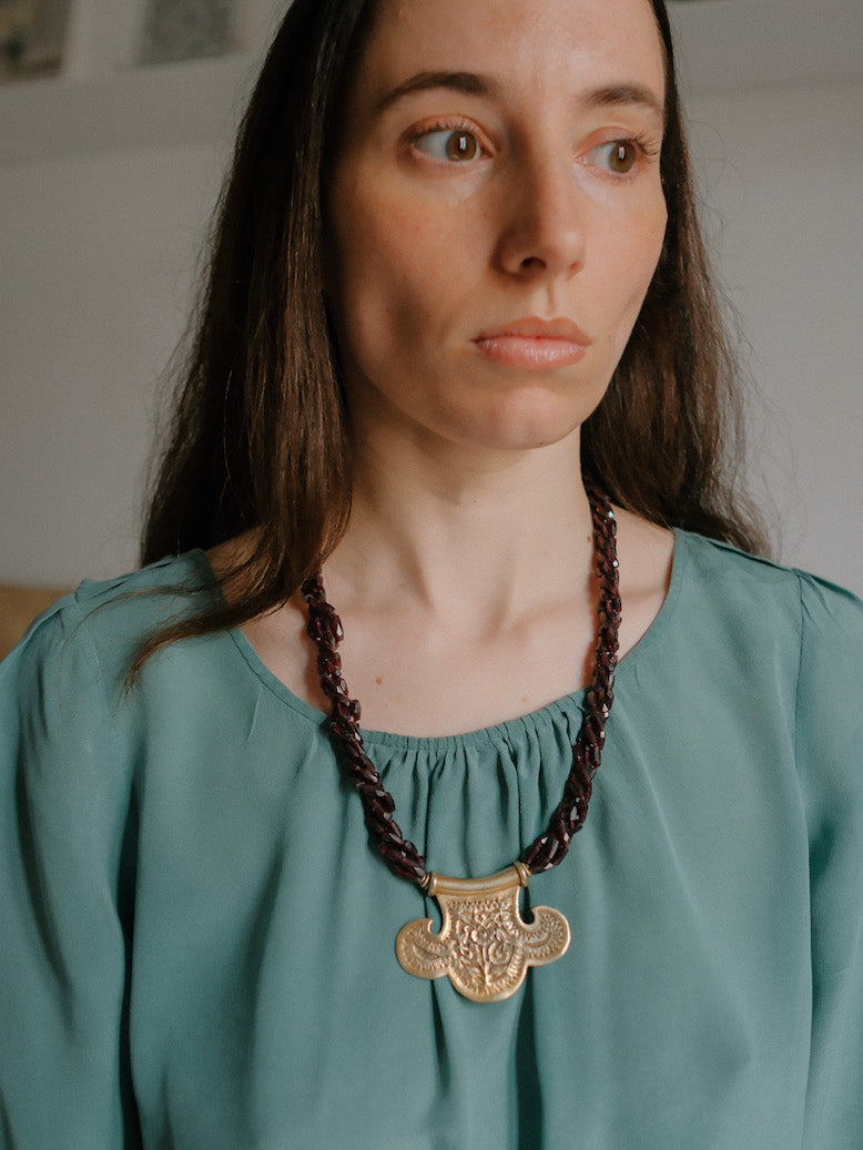 Collar con colgante artesanal hecho a mano con plata de ley dorada y motivos florales, combinada con cuatro vueltas de granates facetados. El cierre es tambien artesanal , de plata de ley dorada. Longitud aproximada 60 cm Medidas colgante 45 cm x 70 cm Peso 120 gr One of a kind by Lula Maiz.