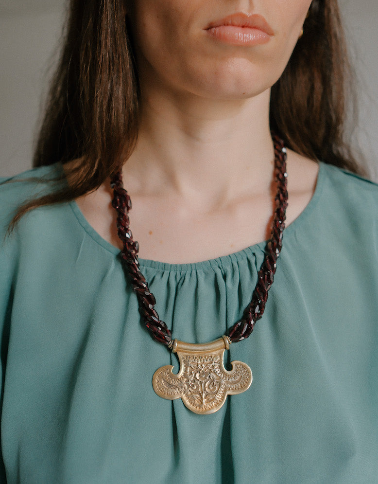 Collar con colgante artesanal hecho a mano con plata de ley dorada y motivos florales, combinada con cuatro vueltas de granates facetados. El cierre es tambien artesanal , de plata de ley dorada. Longitud aproximada 60 cm Medidas colgante 45 cm x 70 cm Peso 120 gr One of a kind by Lula Maiz.