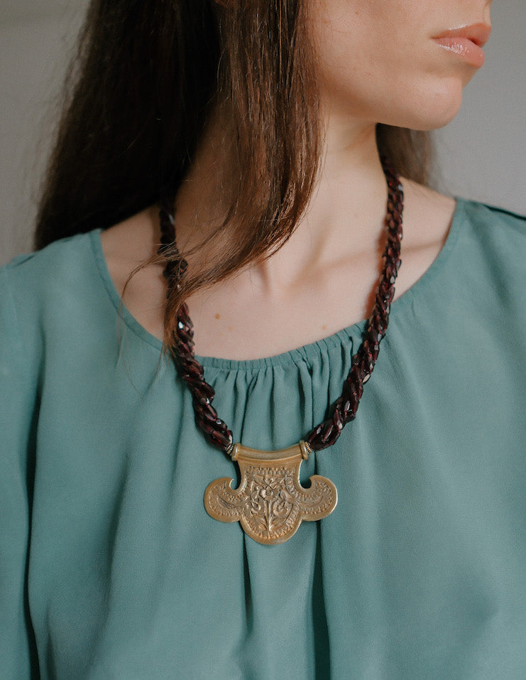 Collar con colgante artesanal hecho a mano con plata de ley dorada y motivos florales, combinada con cuatro vueltas de granates facetados. El cierre es tambien artesanal , de plata de ley dorada. Longitud aproximada 60 cm Medidas colgante 45 cm x 70 cm Peso 120 gr One of a kind by Lula Maiz.