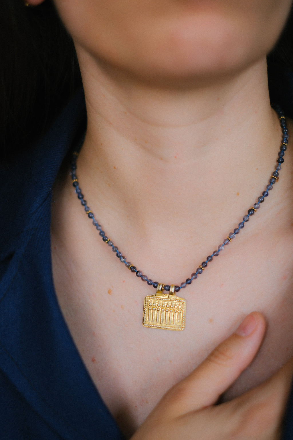 Collar con zafiros de agua  ( iolitas) y antiguo amuleto en plata dorada del Sur de India que representa a las diosas conocidas como las siete hermanas. que son una manifestación de  la Madre Tierra.  El cierre de mosquetón es también de plata dorada. Pieza única diseñada por Lula Máiz. Longitud 43 cm Peso 13 g. One of a kind by Lula Máiz