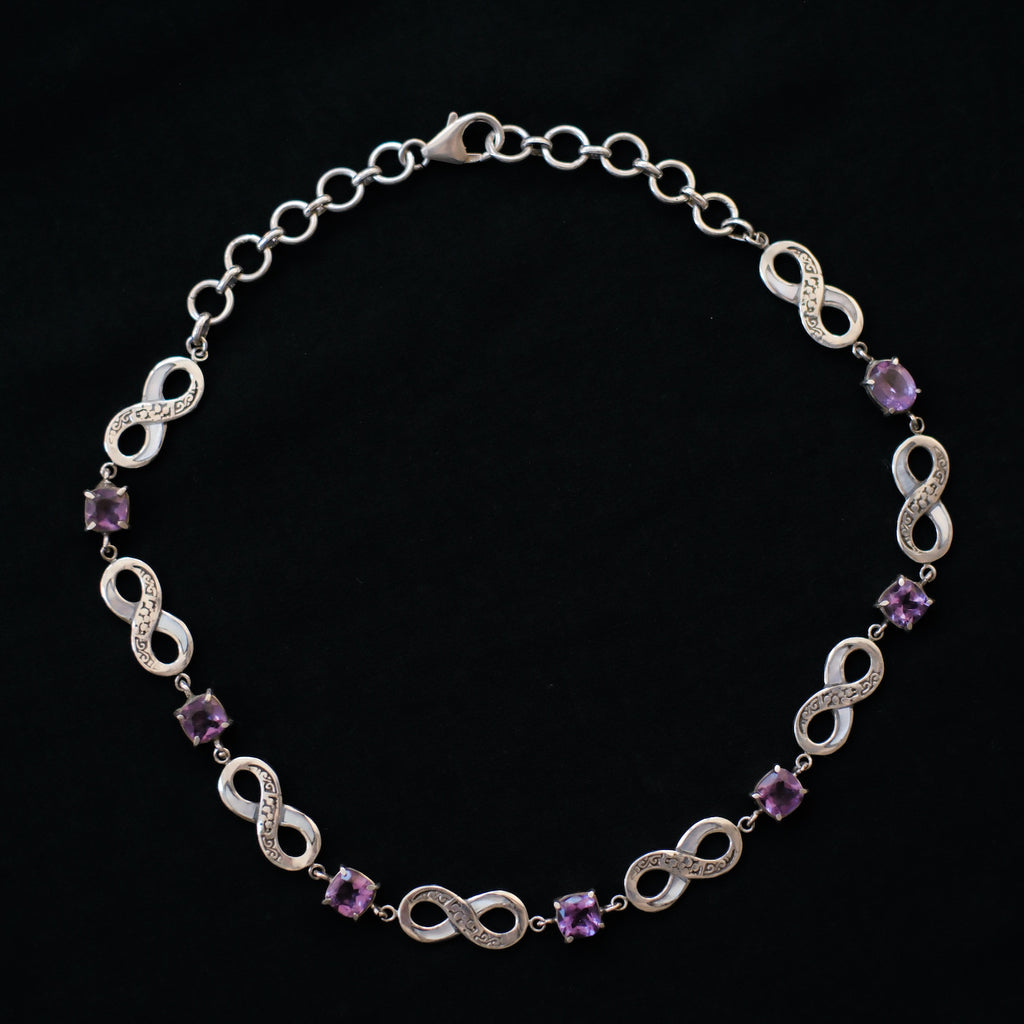 Collar artesanal hecho a mano con plata de ley, símbolos del infinito y 7 amatistas cuadradas facetadas. El cierre es de mosquetón. Tamaño adaptable, 38 cm a 43 cm Peso 29 g.Handcrafted silver necklace with  7 faceted amethyst. Lula Máiz