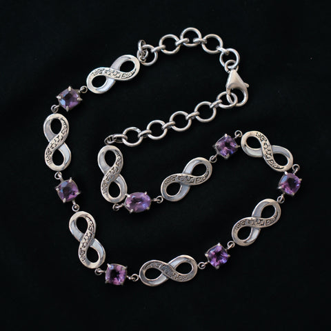 Collar artesanal hecho a mano con plata de ley, símbolos del infinito y 7 amatistas cuadradas facetadas. El cierre es de mosquetón. Tamaño adaptable, 38 cm a 43 cm Peso 29 g.Handcrafted silver necklace with  7 faceted amethyst. Lula Máiz