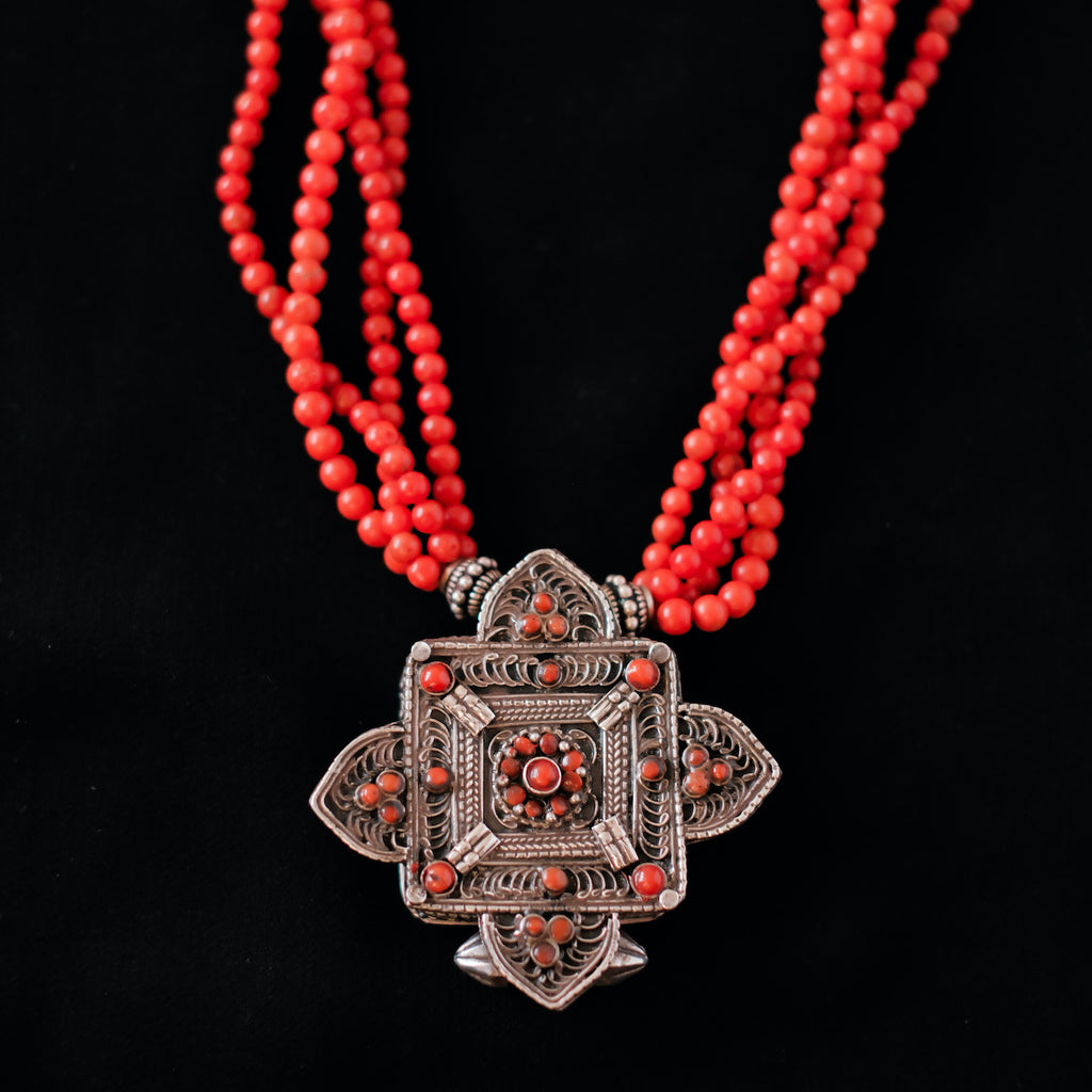 Collar con ghau ,colgante caja amuleto de plata y coral tibetano, engarzado con cuatro vueltas de coral rojo y cuentas de plata de ley. El cierre es también de plata y coral. Longitud 75 cm ( puede ajustarse enrollando las vueltas de coral en mayor o menor grado) Peso 100 g. One of a kind necklace by Lula M