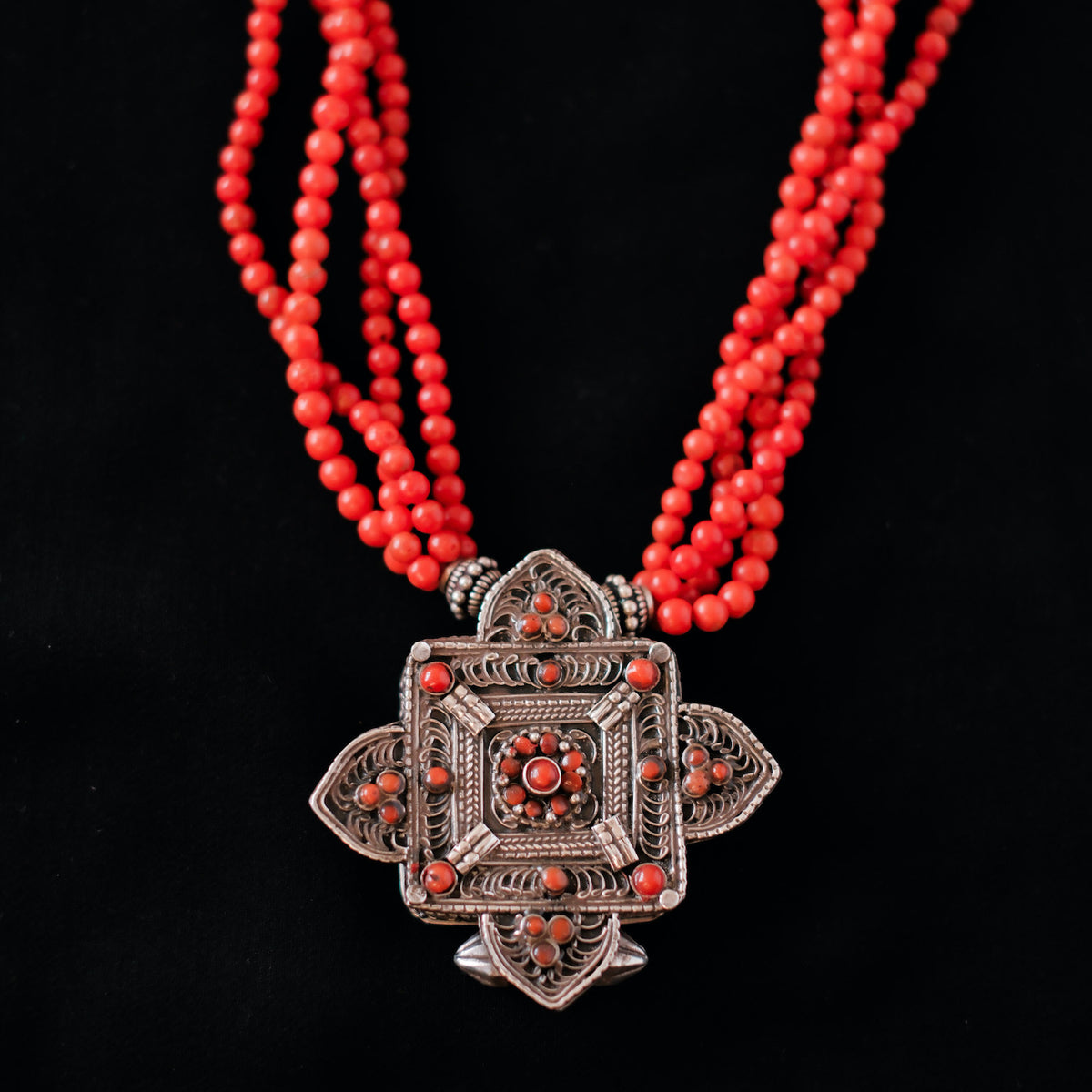 Collar con ghau ,colgante caja amuleto de plata y coral tibetano, engarzado con cuatro vueltas de coral rojo y cuentas de plata de ley. El cierre es también de plata y coral. Longitud 75 cm ( puede ajustarse enrollando las vueltas de coral en mayor o menor grado) Peso 100 g. One of a kind necklace by Lula M