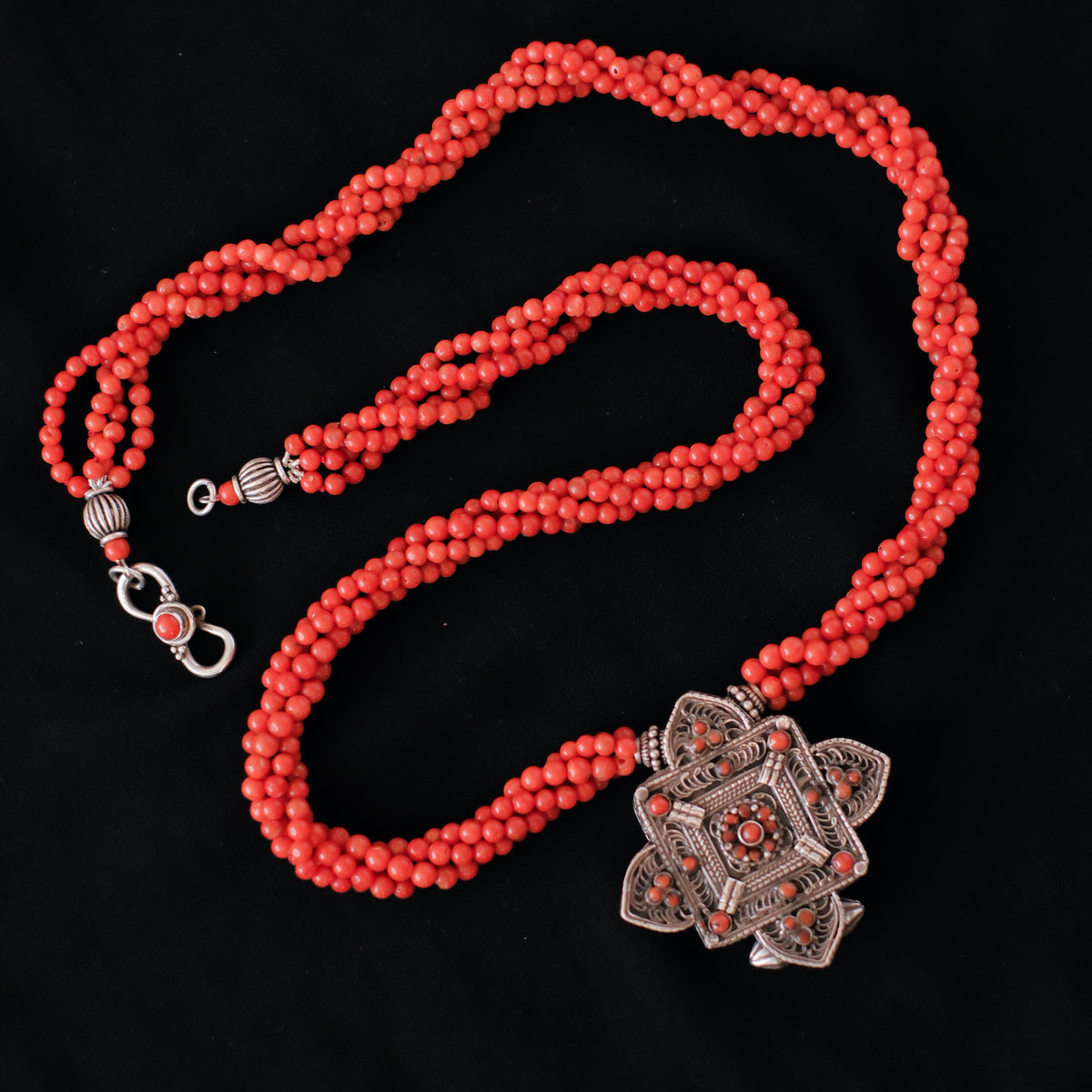 Collar con ghau ,colgante caja amuleto de plata y coral tibetano, engarzado con cuatro vueltas de coral rojo y cuentas de plata de ley. El cierre es también de plata y coral. Longitud 75 cm ( puede ajustarse enrollando las vueltas de coral en mayor o menor grado) Peso 100 g. One of a kind necklace by Lula M