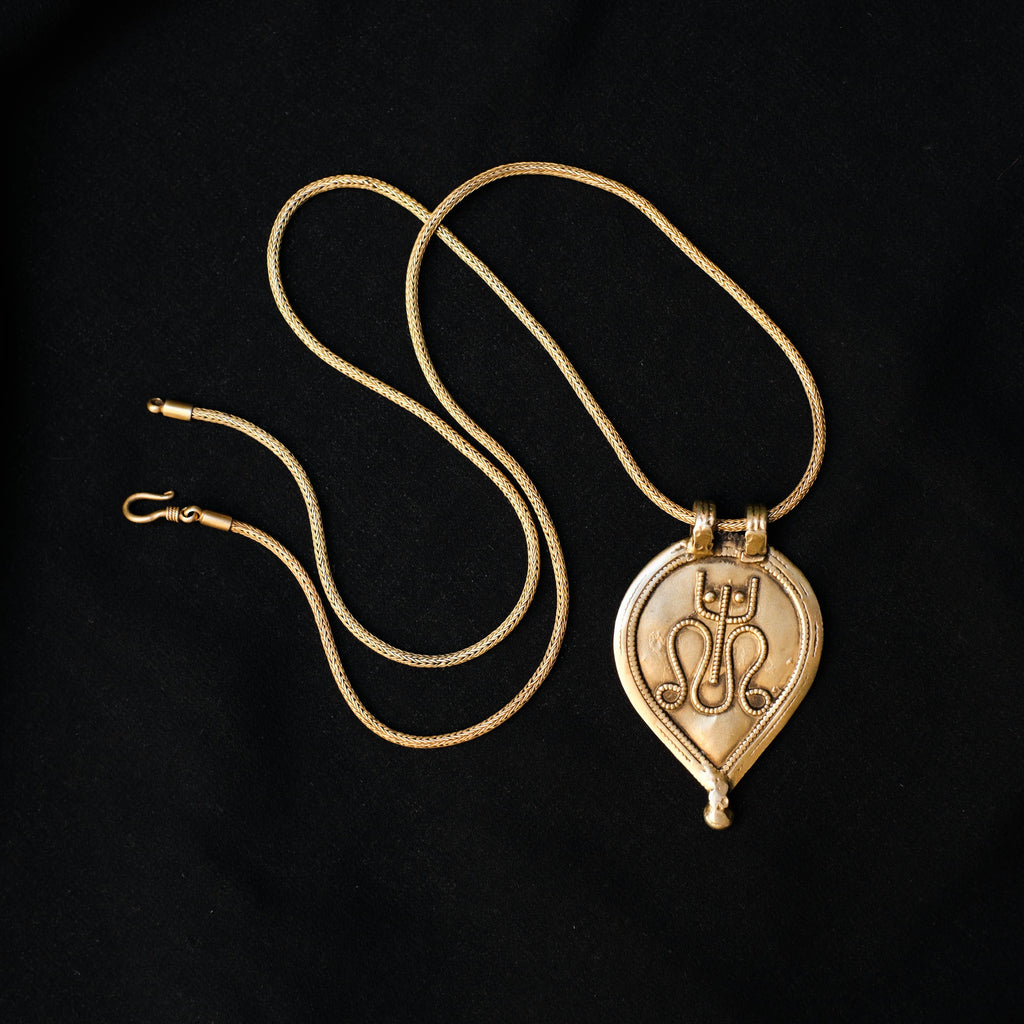 Antiguo amuleto de India en plata dorada con una serpiente y un tridente, símbolos de Shiva, dios supremo del hinduismo que crea, protege y transforma el universo. La cadena artesanal hecha a mano con plata de ley y baño de oro. Colgante.  Medidas 6 cm x 4 cm. Peso 13 g. Cadena. Longitud 66 cm. Grosor 2 mm Old Shiva amulet. Old indian amulets. Lula Máiz