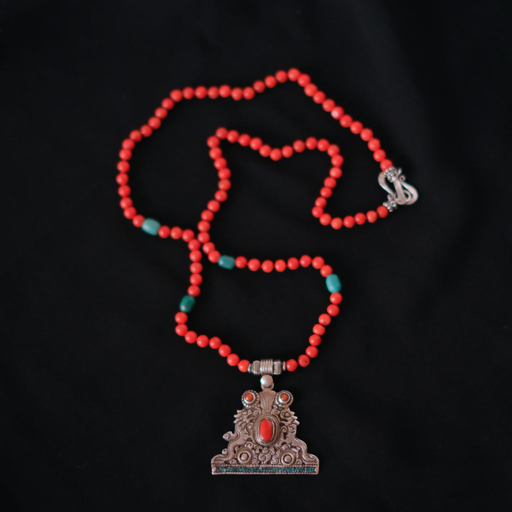 Collar con colgante tibetano de plata hecho a mano representando dos dragones, animal mitológico que para los budistas representa buena suerte, fuerza y salud. Combinado en esta pieza única de Lula Máiz con coral y turquesa. El cierre es de plata de ley. Longitud 60 cm Peso 32 g One of a kind by Lula Máiz