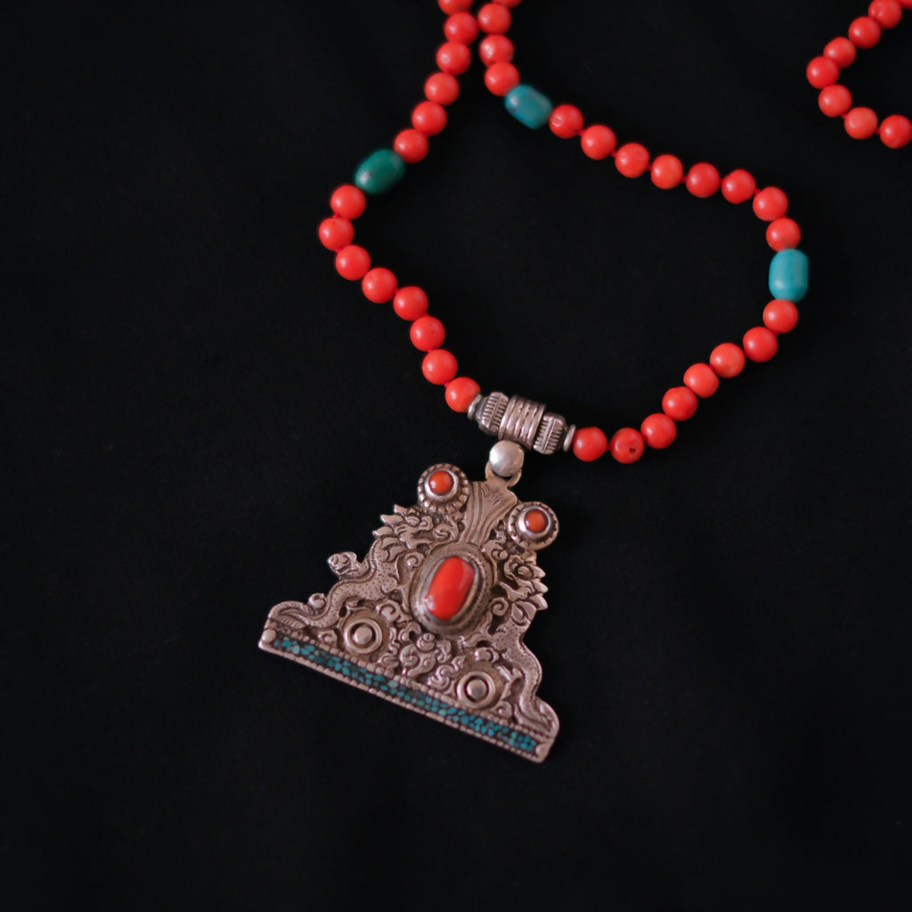 Collar con colgante tibetano de plata hecho a mano representando dos dragones, animal mitológico que para los budistas representa buena suerte, fuerza y salud. Combinado en esta pieza única de Lula Máiz con coral y turquesa. El cierre es de plata de ley. Longitud 60 cm Peso 32 g One of a kind by Lula Máiz