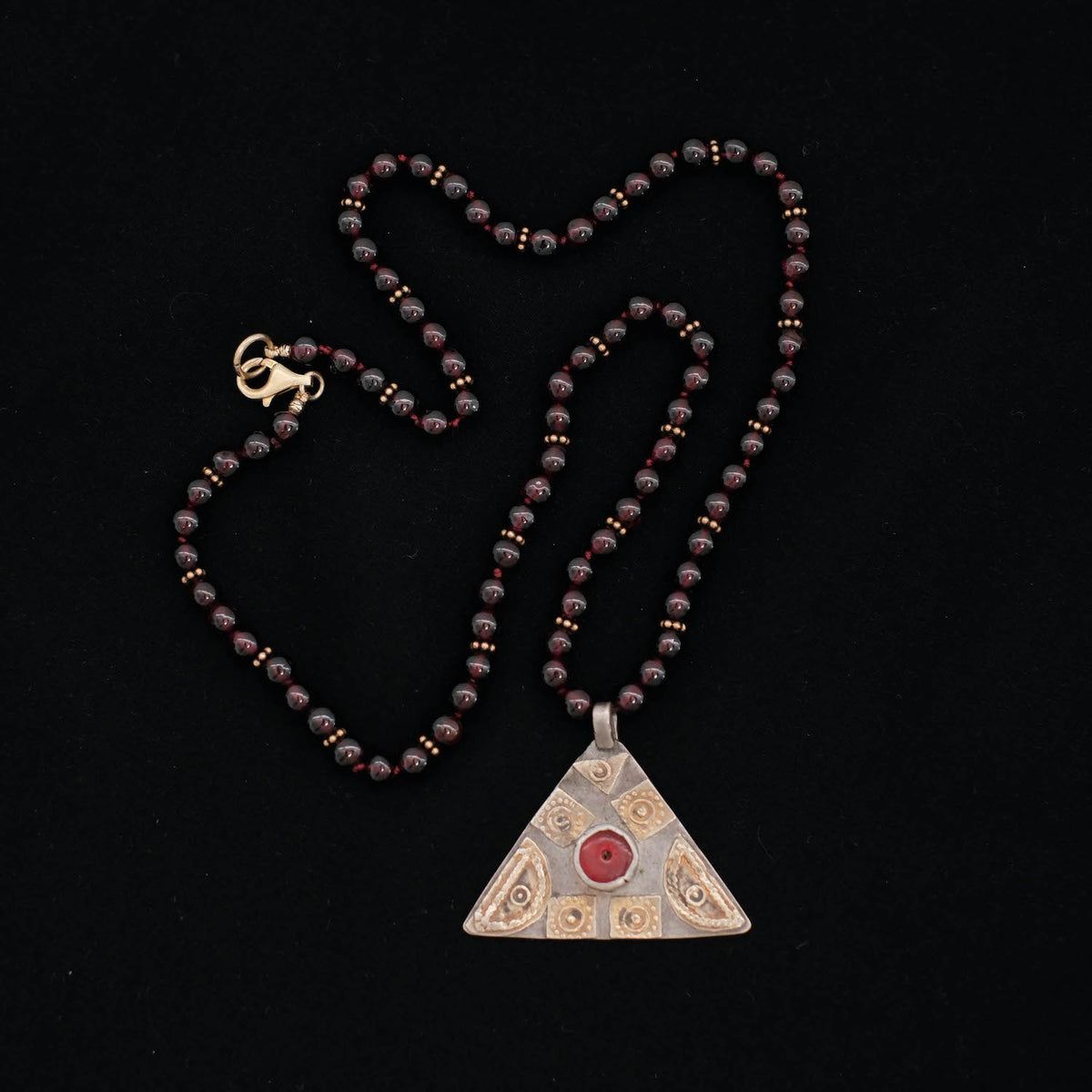 Collar diseñado por Lula Máiz con un colgante antiguo en plata , baño de oro y vidrio central de los Yomud ( etnia nómada de Turkmenistán ), montado con granates y cuentas de plata con baño de oro. El cierre de mosquetón es contemporáneo, también en plata chapada. Pieza única. Longitud 46 cm. Peso 28 g. One of a kind by Lula Máiz. Old  pendant.