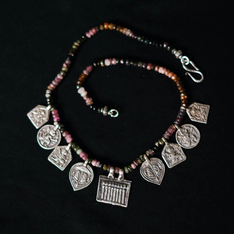 Collar con turmalinas multicolores y amuletos antiguos de India hechos con plata. Representan diversas deidades hindúes y tribales, como las Siete Hermanas, Hanuman el dios mono, las huellas del dios Vishnu, también conocido con el nombre de Narayana. El cierre es contemporáneo de plata de ley. Longitud 46 cm Peso 40 g. Pieza única, diseño de Lula Máiz. One of a kind by Lula Máiz