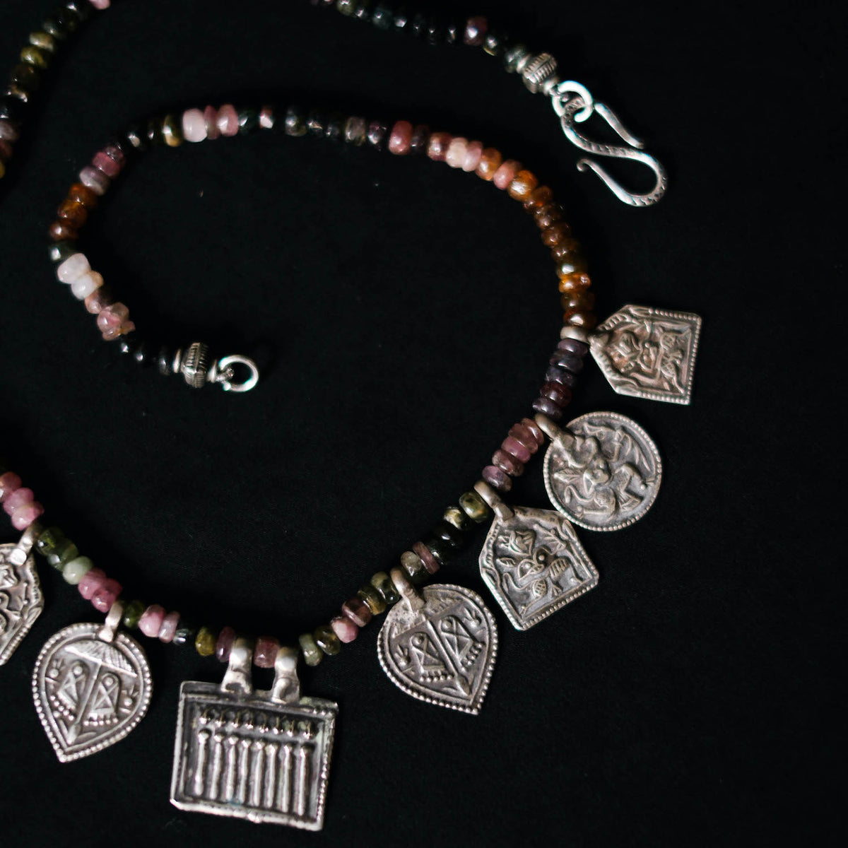 Collar con turmalinas multicolores y amuletos antiguos de India hechos con plata. Representan diversas deidades hindúes y tribales, como las Siete Hermanas, Hanuman el dios mono, las huellas del dios Vishnu, también conocido con el nombre de Narayana. El cierre es contemporáneo de plata de ley. Longitud 46 cm Peso 40 g. Pieza única, diseño de Lula Máiz. One of a kind by Lula Máiz