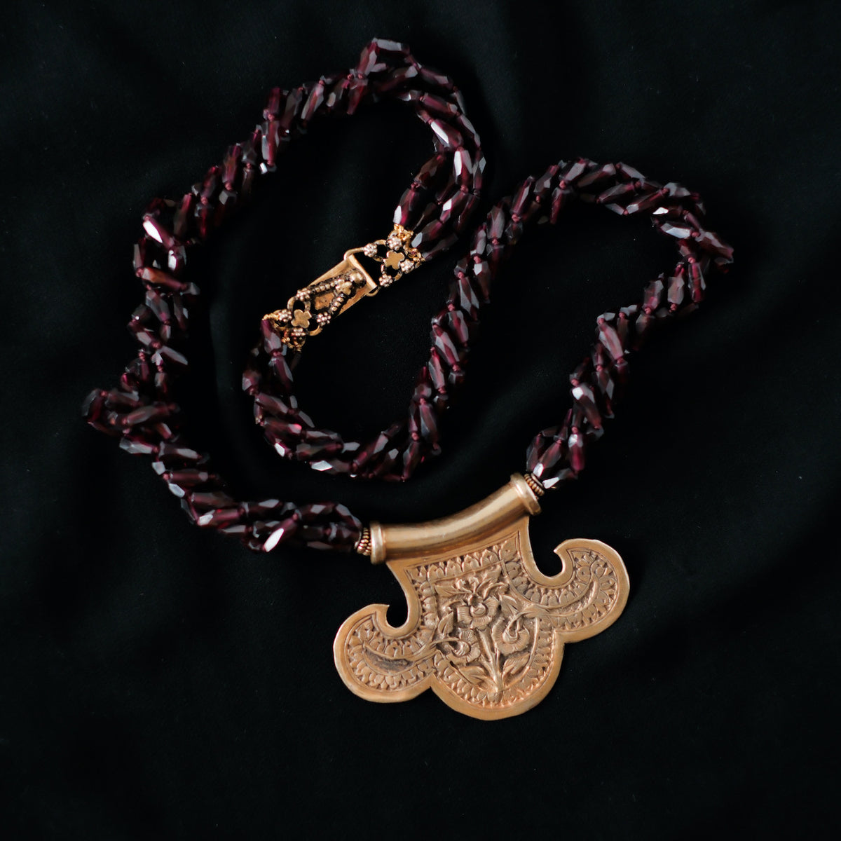 Collar con colgante artesanal hecho a mano con plata de ley dorada y motivos florales, combinada con cuatro vueltas de granates facetados. El cierre es tambien artesanal , de plata de ley dorada. Longitud aproximada 60 cm Medidas colgante 45 cm x 70 cm Peso 120 gr One of a kind by Lula Maiz.