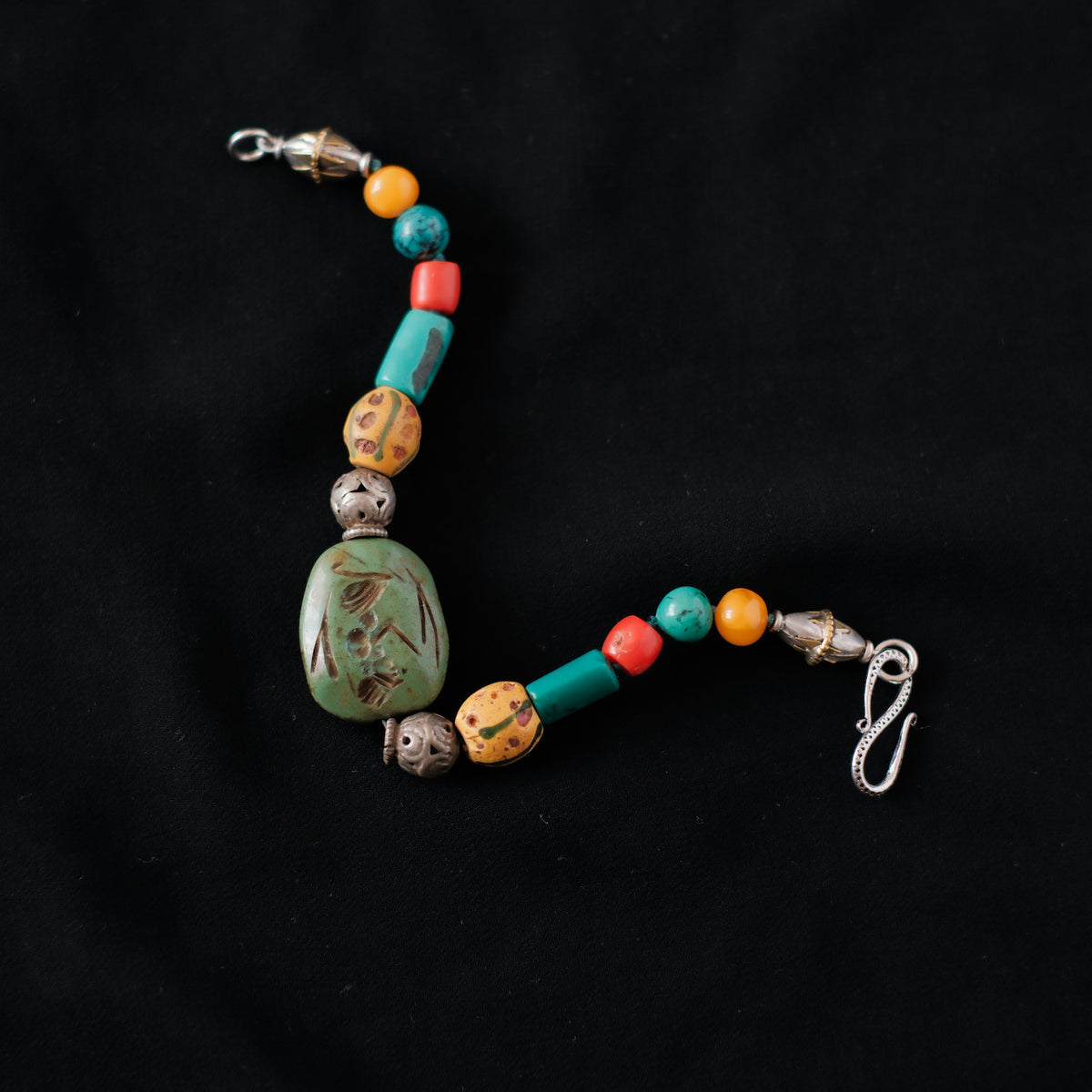 Pulsera con turquesa tibetana con figura antropomorfica tallada, combinada con antiguas cuentas de vidrio de Murano, coral, turquesa, ámbar y cuentas de plata antigua de Paquistán. El cierre es contemporáneo, de plata de ley. Longitud 19 cm Peso 28 gr One of a kind bracelet by Lula Maiz