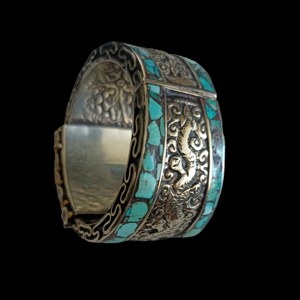 Brazalete artesanal tibetano hecho a mano con aleación de plata y coral y turquesa prensados. Decorada con 2 dragones, El dragón es símbolo de fuerza, coraje y sabiduría en Oriente y portador de buena suerte.   Se abre por la parte posterior mediante bisagras.  Contorno interior 17 cm  Apertura  máxima 2´5 cm Ancho 5 cm Peso  150 g. Hand made tibetan cuff bracelet