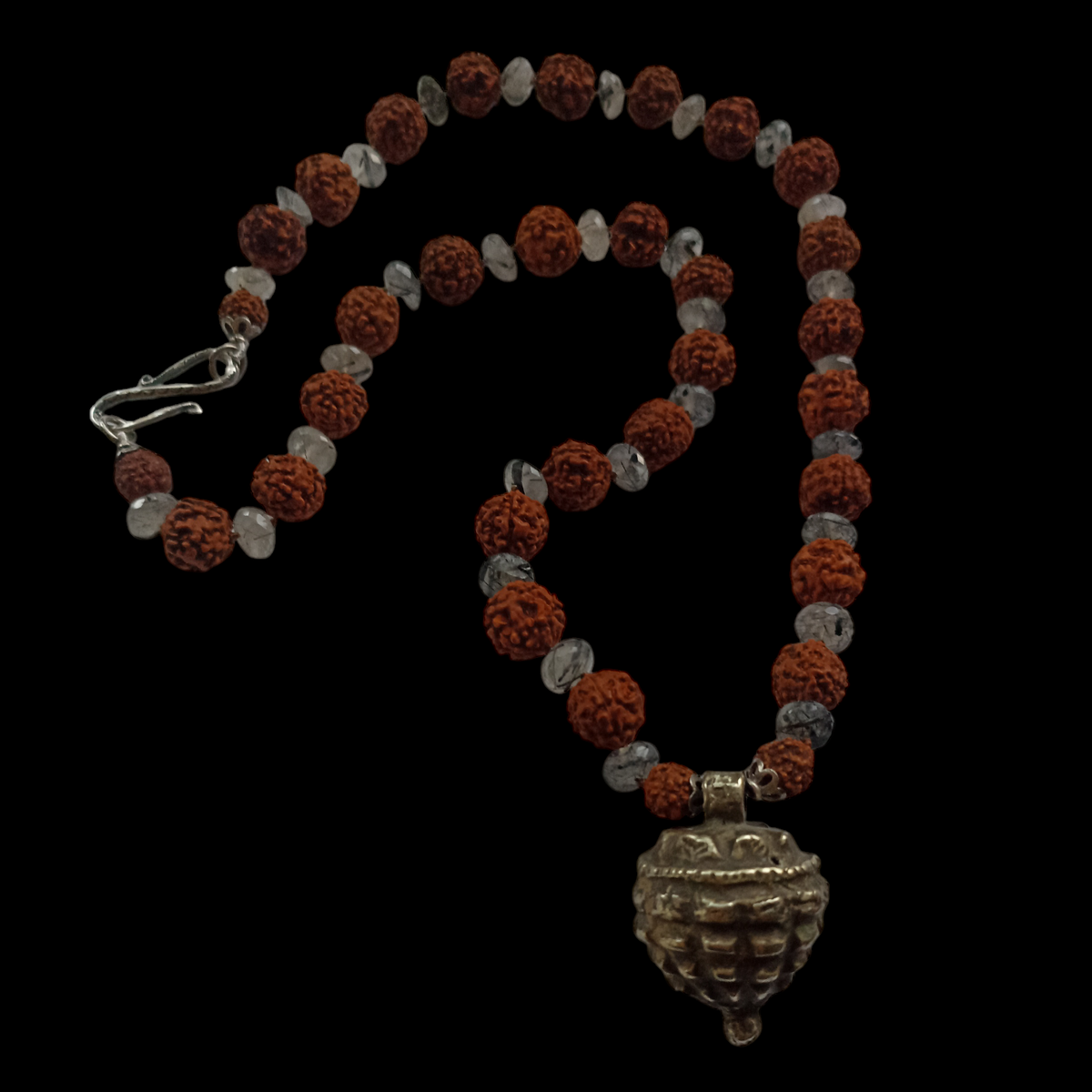 Collar con semillas de rudraksha, estas semillas (también llamadas lagrimas de Shiva ) se usan tradicionalmente para orar en el budismo e hinduismo,asi como en en la medicina tradicional india por sus supuestas propiedades curativas. El colgante antiguo de plata es de India y va engarzado con cuentas de cuarzo rutilado negro. El cierre es contemporáneo, también de plata. Longitud 56 cm Peso 53 g.One of a kind by Lula Máiz.