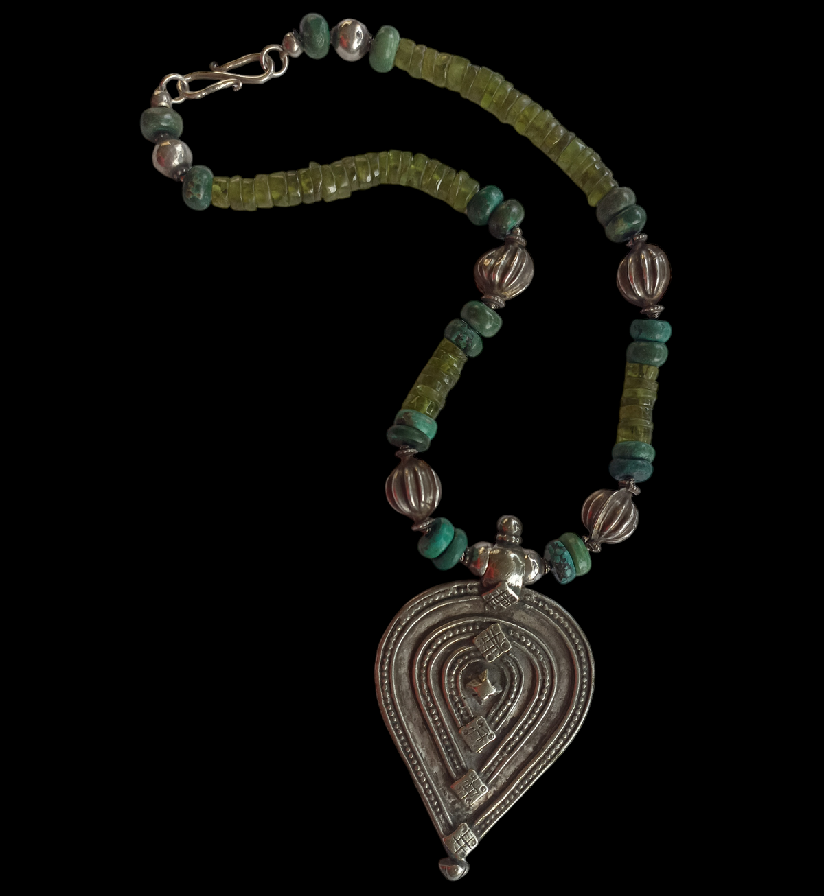 Collar con colgante de plata antiguo de India con forma de yoni y lingam ( Shakti y Shiva ) representando la unión de los principios femenino y masculino que simbolizan la fuerza vital del Universo, engarzado con discos de peridoto, turquesas y cuentas de plata antigua de India. El cierre es contemporáneo, de plata de ley. Pieza única de Lula Máiz. One of a kind by Lula Máiz