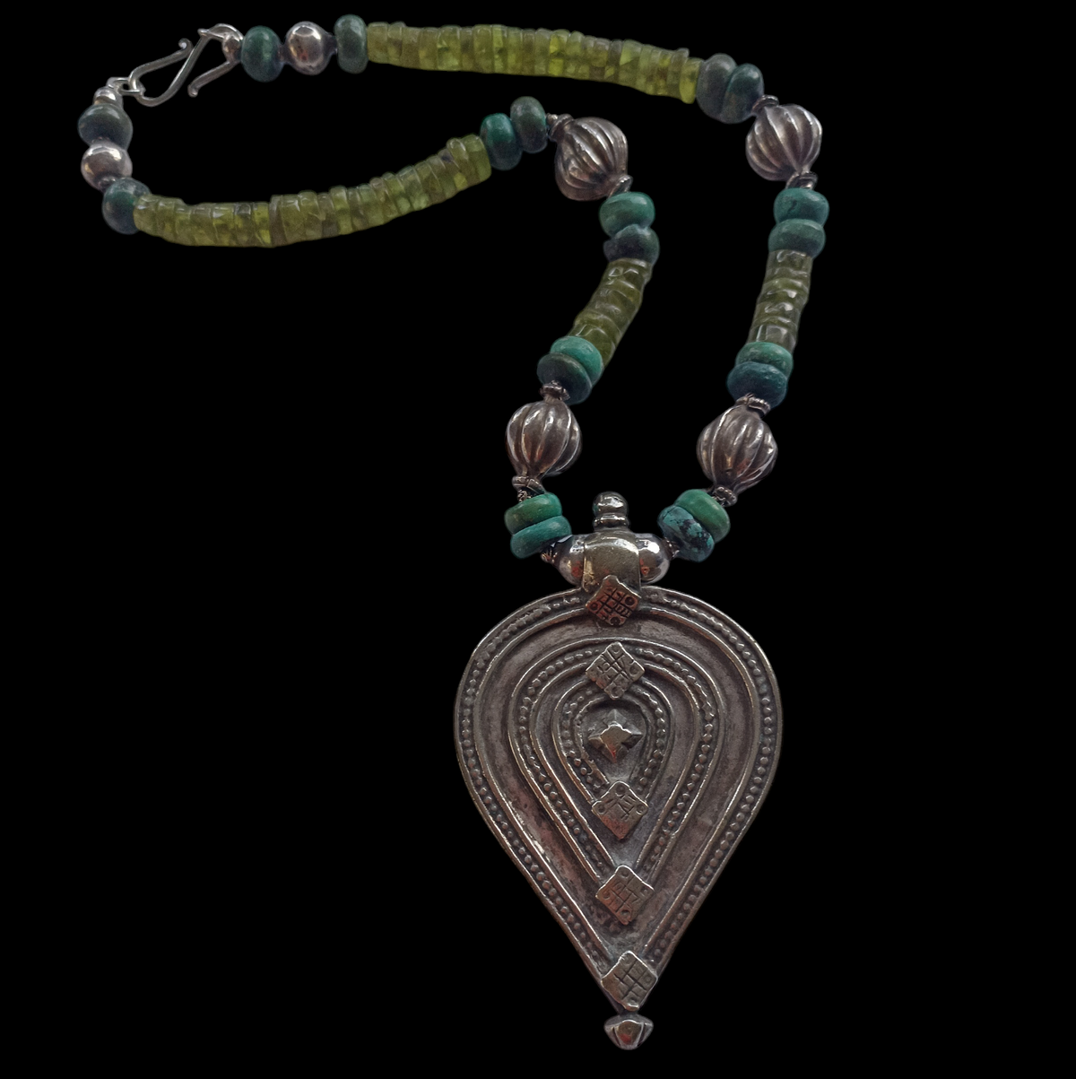 Collar con colgante de plata antiguo de India con forma de yoni y lingam ( Shakti y Shiva ) representando la unión de los principios femenino y masculino que simbolizan la fuerza vital del Universo, engarzado con discos de peridoto, turquesas y cuentas de plata antigua de India. El cierre es contemporáneo, de plata de ley. Pieza única de Lula Máiz. One of a kind by Lula Máiz