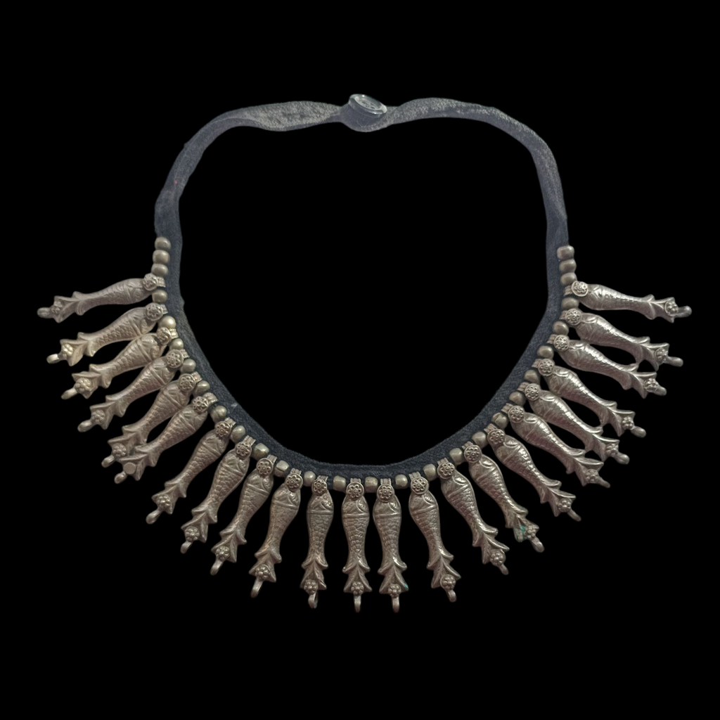 Collar antiguo del pueblo nómada Kuchi, que viven en Afganistán. Esta hecho a mano con plata y conserva el algodón original y el botón de cierre. Los peces son muy venerados en muchas culturas tribales porque se asocian con el agua, fuente de vida. Longitud 50 cm Longitud peces 5 cm Peso 115 g Old Kuchi necklace. Lula Máiz