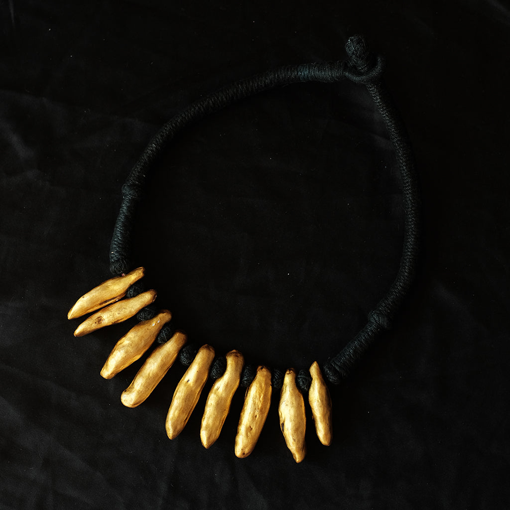 Collar étnico con piezas de cera recubiertas con oro y montadas sobre algodón negro. Contorno 48 cm. Peso 67 g.