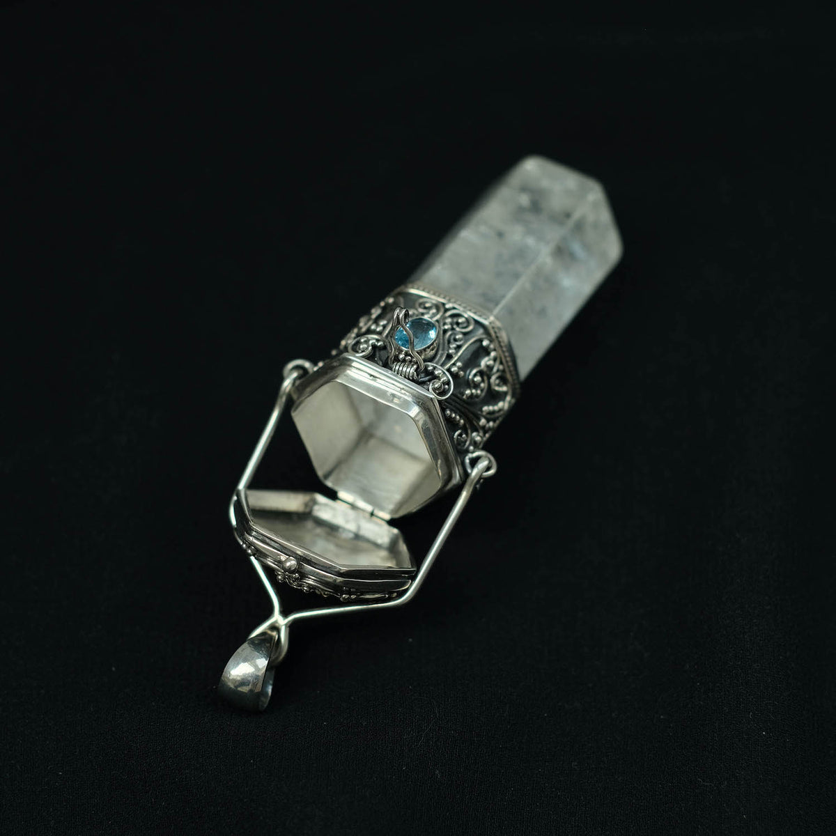 Colgante artesanal de cristal de cuarzo montado con plata de ley trabajada con la técnica de granulación y un topacio azul. La parte superior es una caja. Longitud 9 cm ( el colgante 6 cm) Diámetro 2´5 cm Peso 47 g. &nbsp; Healing crystals.